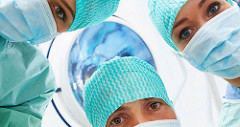 Three surgeons view in an operating room wearing full operation gown staring downwards